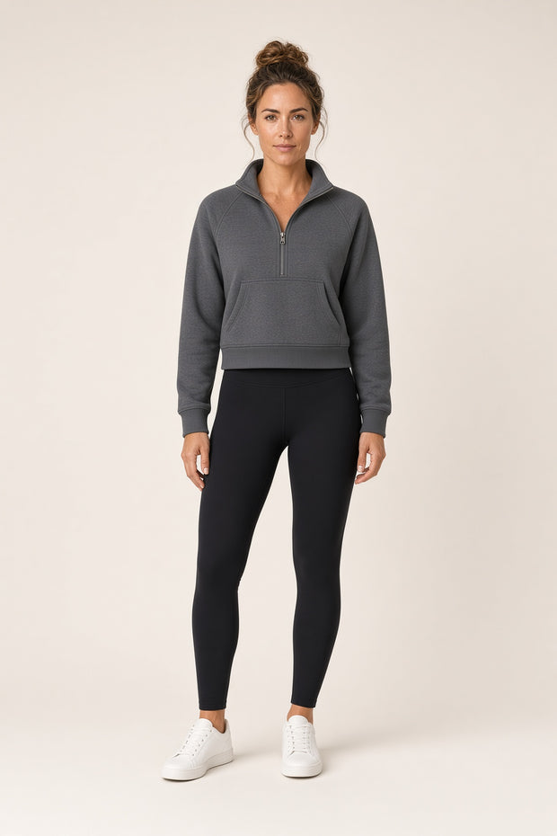 Woman wearing the Tuvi Cropped Half-Zip Sweatshirt in grey with black leggings