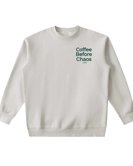 Tuvi Coffee Before Chaos crewneck sweatshirt in light beige with dark green chest text on a plain background.