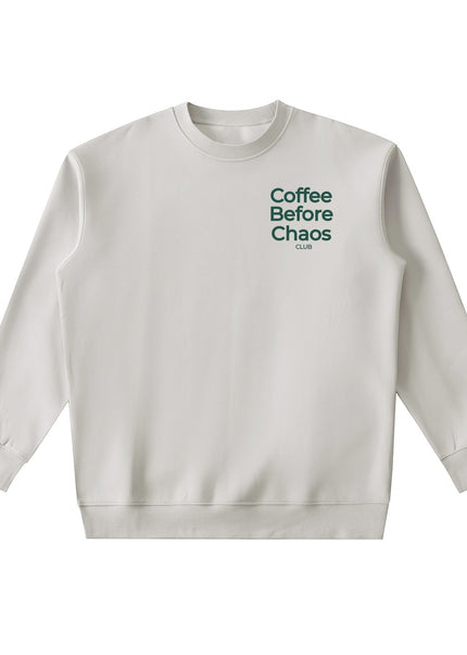 Tuvi Coffee Before Chaos crewneck sweatshirt in light beige with dark green chest text on a plain background.