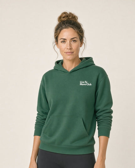 Woman wearing the Tuvi Live To Move Hoodie in Eden Green, with the white Live To Move Club chest print and a kangaroo pocket, styled with black leggings.